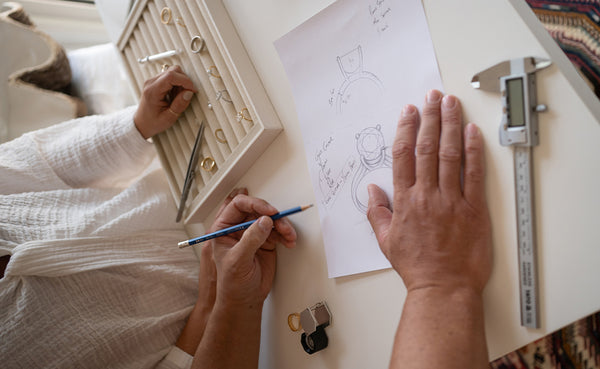 Saint Stones founders Ashlynne and Ben working on jewelry design with tools and sketches on a table, styled for luxury bridal jewelry creation in Colorado