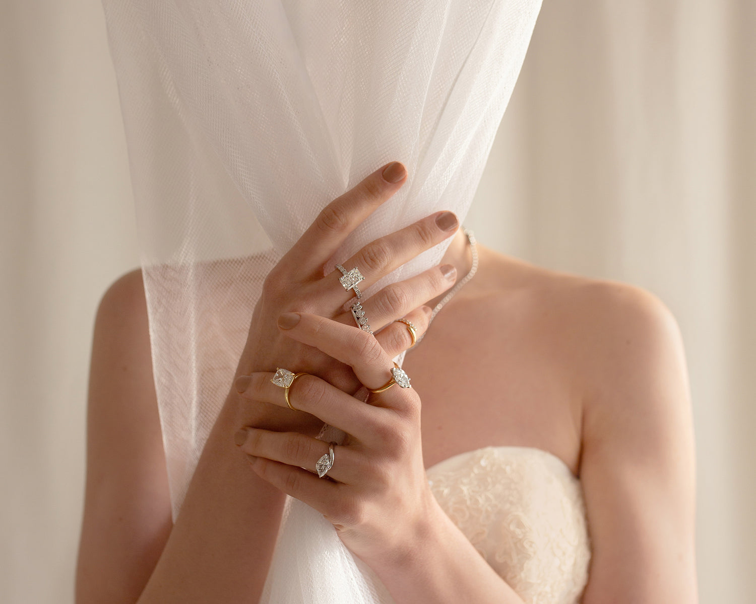 Close-up of a Saint Stones model wearing multiple rings while holding a bridal veil. Elegant bridal jewelry for weddings in Fort Collins, Denver, and throughout Colorado.