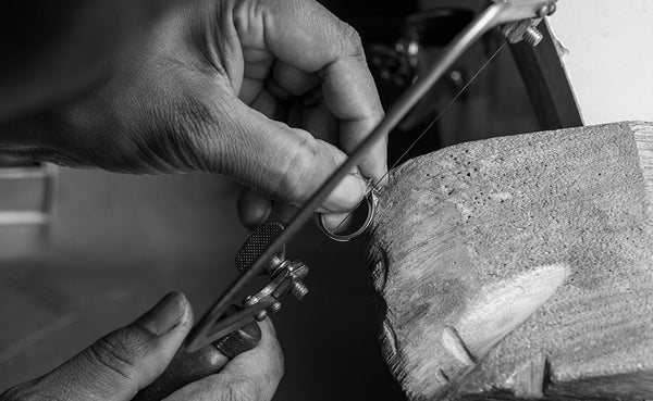 Saint Stones workshop scene showing scissors cutting a piece of wood on a concrete surface, styled for jewelry design and crafting photography in Colorado